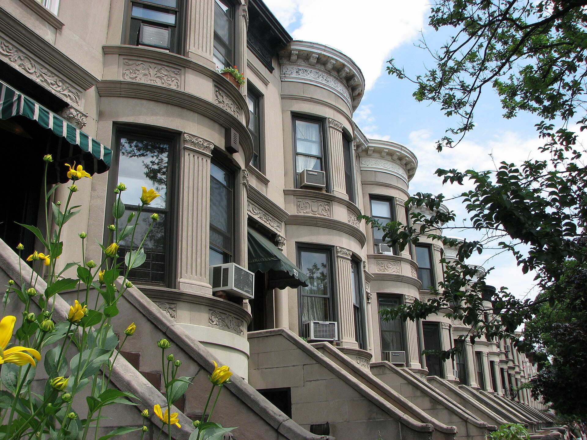 Row of limestone townhouses with stoops and spring flowers in Park Slope, Brooklyn